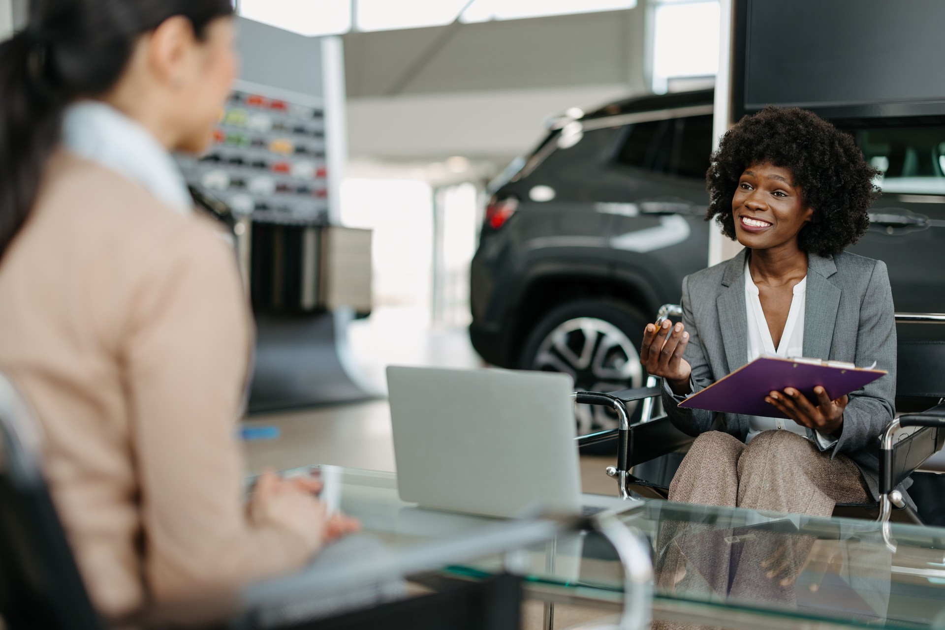 Saleswoman presents car key in a dealership