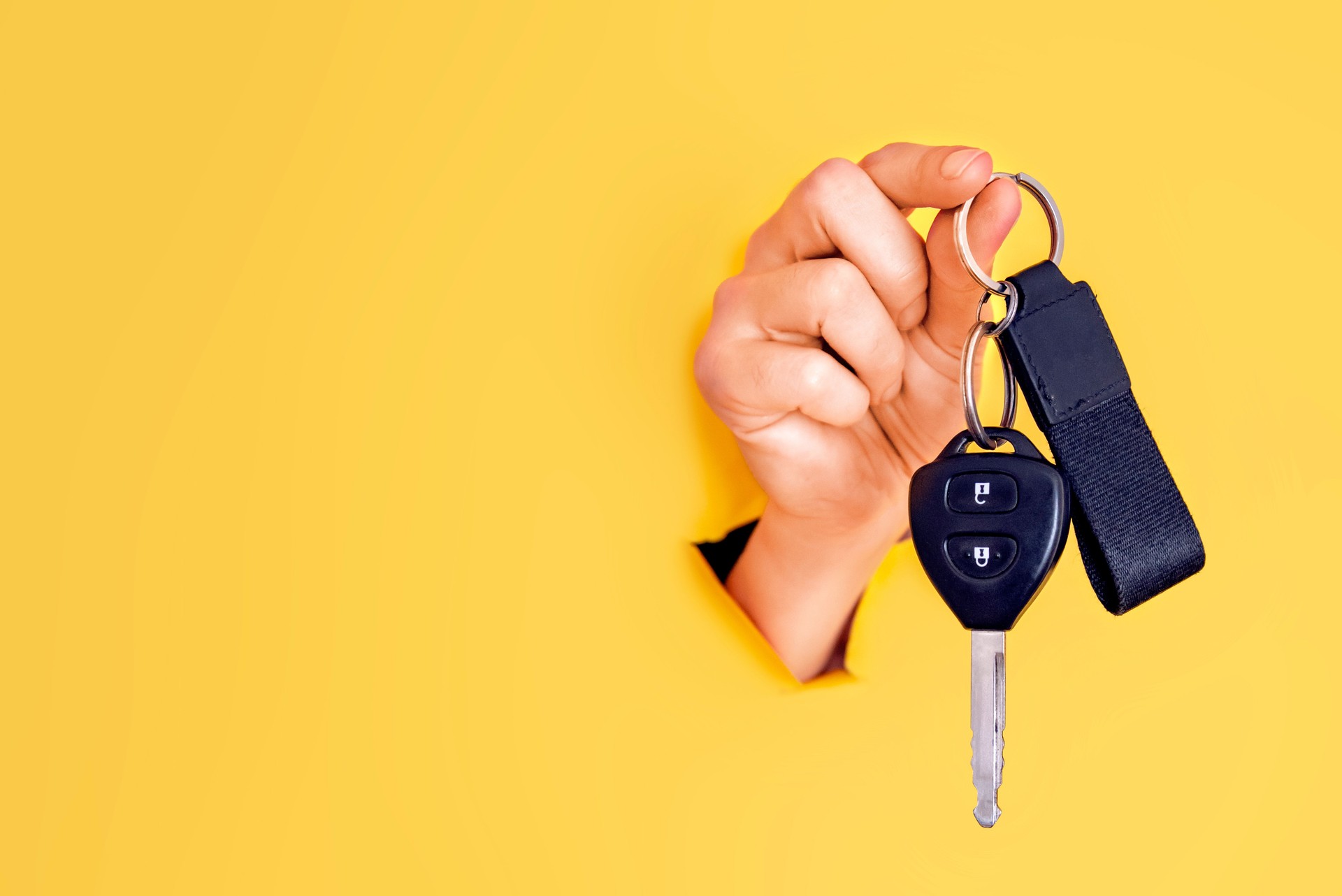 Female car salesperson holding a car key.