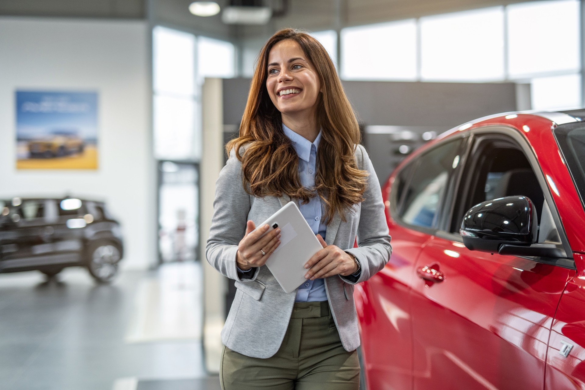 Professional car sales consultant standing at auto dealership