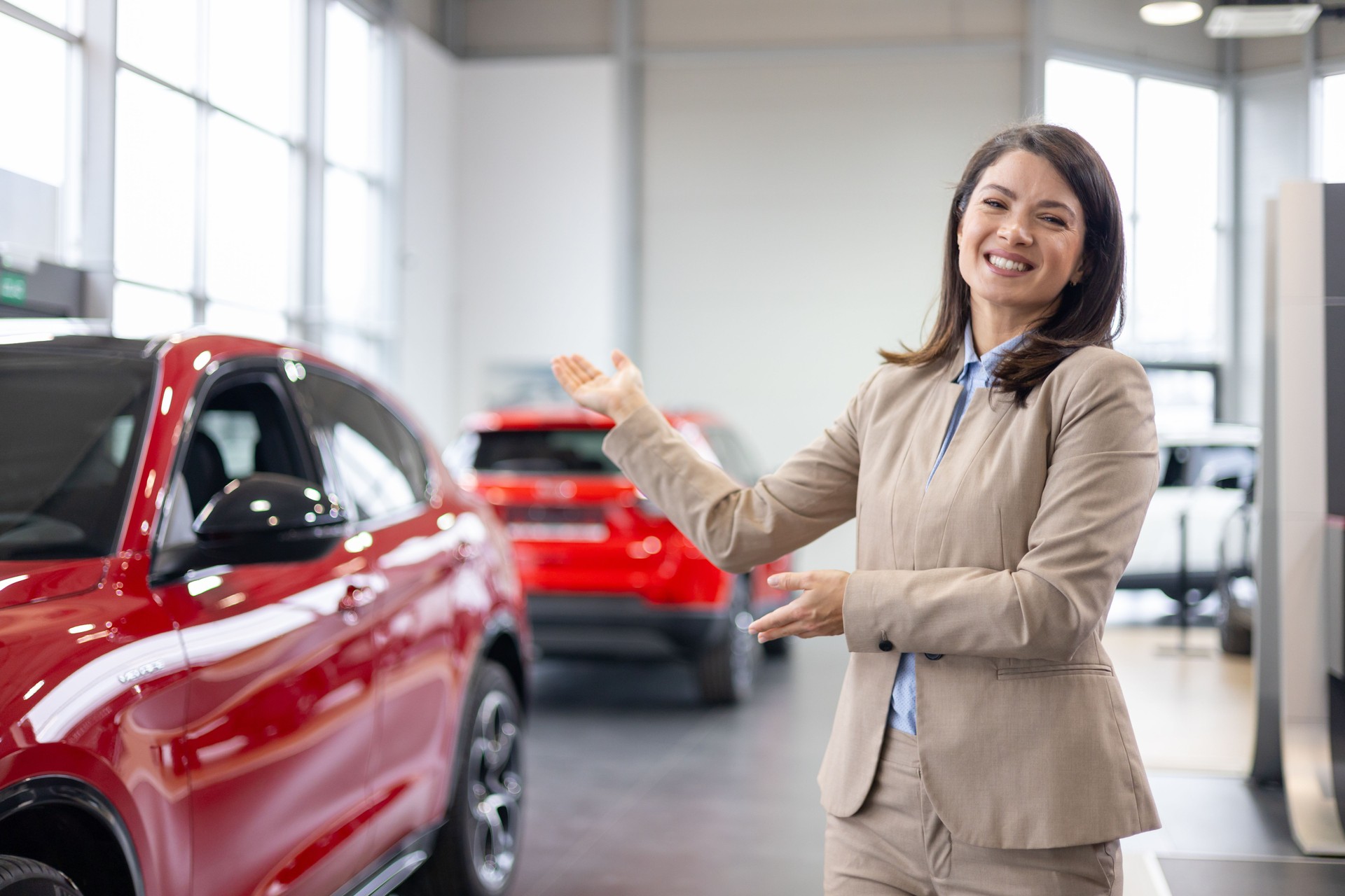 Car salesman with outstretched arms in showroom