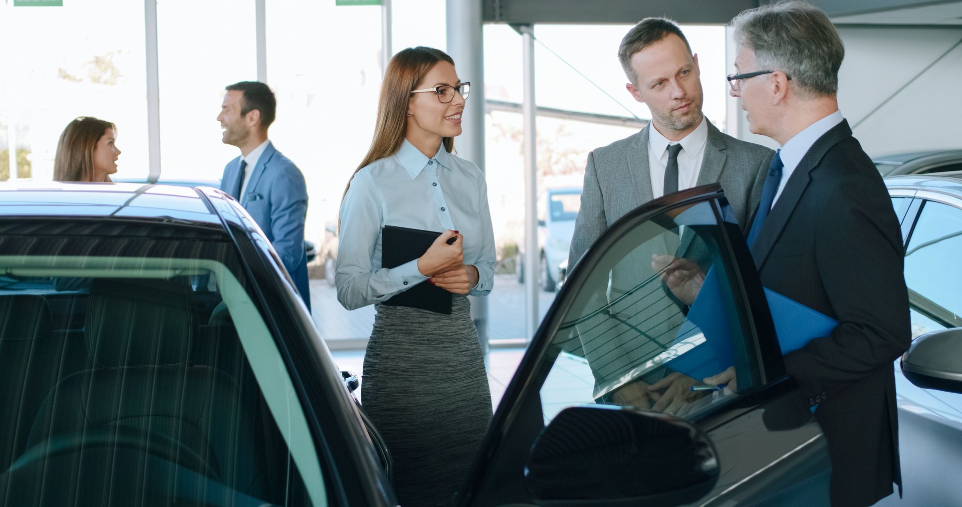 Car salespersons discussing business strategy at car dealership